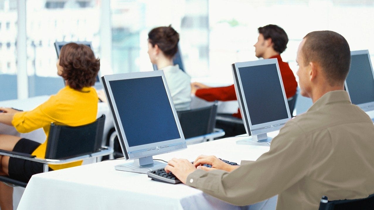 Rear view of four business executives using computers in an office
