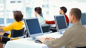  rear view of four business executives using computers in an office