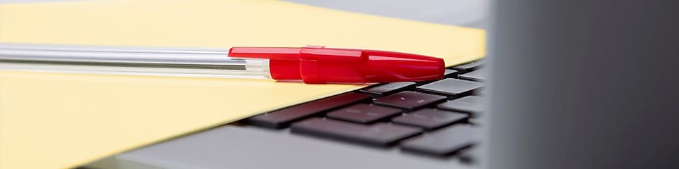 Red pen and yellow sheet of paper on the keyboard of a laptop BUSINESS ENVIRONMENT UK 2010