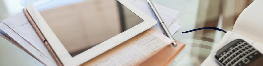 Tablet computer, newspaper, coffee cup and cell phone on desk